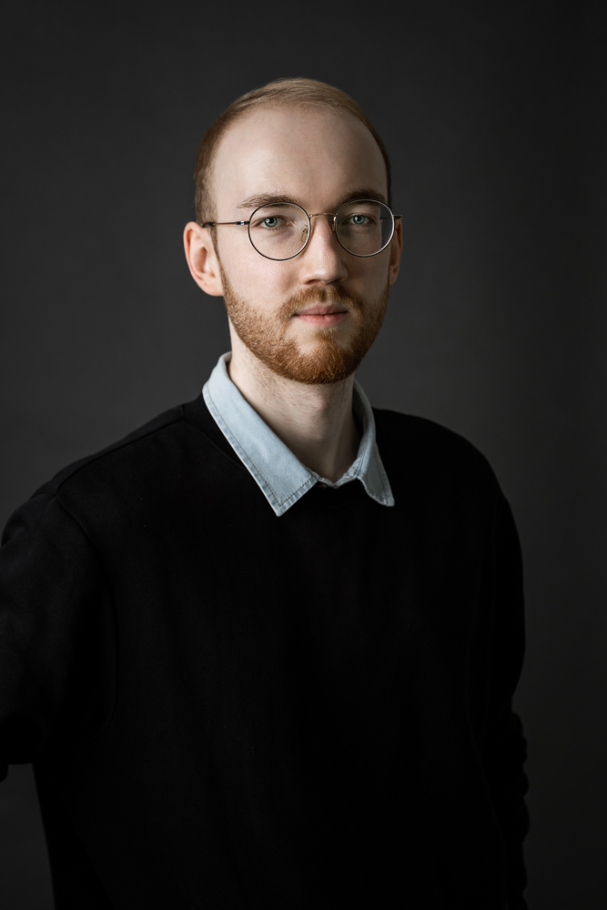 Yannik-ansprechpartner-light-photography-brille-spiegelung-stormgrey-background