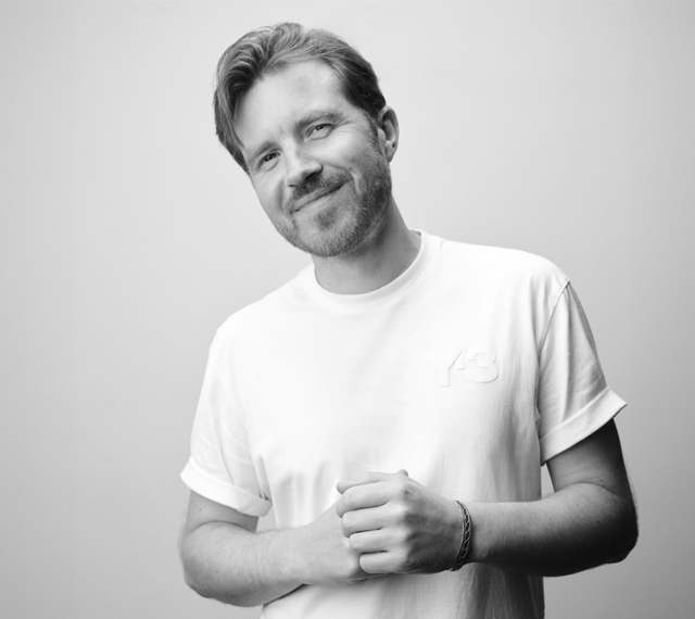 Fotograf Mats Karlsson Studioportrait Mats-Karlsson-Schwarz-weiss-portrait-neu-weisse-leinwand-studio-sympathischer-blick-leichtes-laecheln-haende-zusammen-vor-obberkoerper-dynamische-haltung